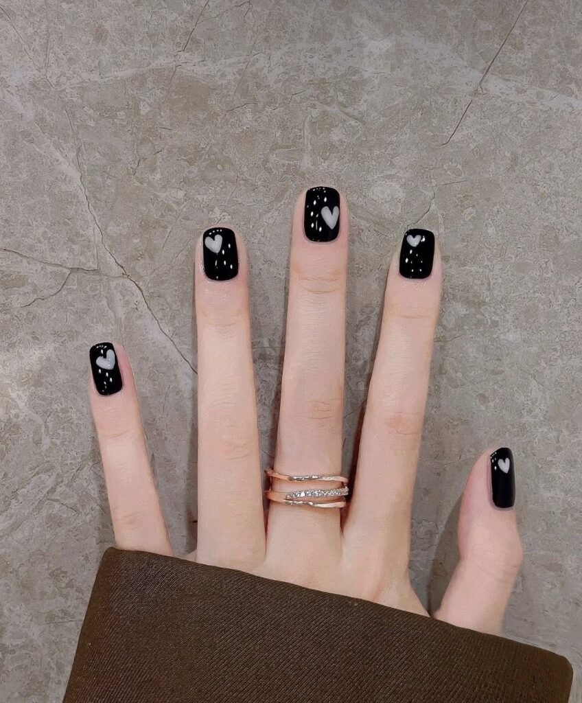 Nail tay đẹp phong cách tối giản với gam đen bóng gương xuyên suốt, điểm xuyết họa tiết trái tim trắng nhỏ dễ thương, cá tính.