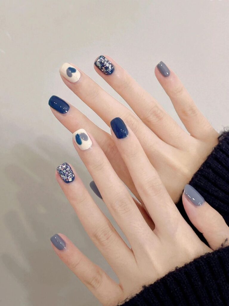 Bộ nail đẹp phối hài hòa giữa xanh navy, xám khói và trắng kem, điểm nhấn nhũ sequin lấp lánh và họa tiết trái tim nhỏ, ấm áp mùa đông.