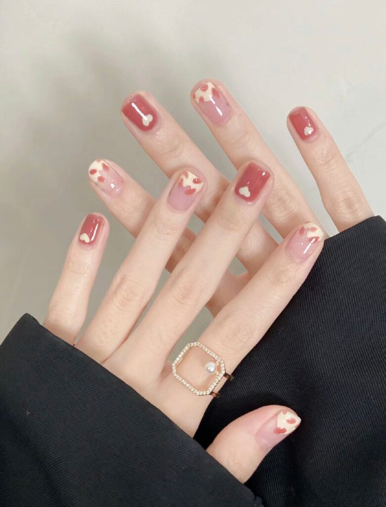 Những bộ nail đẹp phối tông đỏ hồng gạch và trắng ngà, điểm xuyết họa tiết mây bồng bềnh cùng trái tim nhỏ, ngọt ngào và nữ tính.