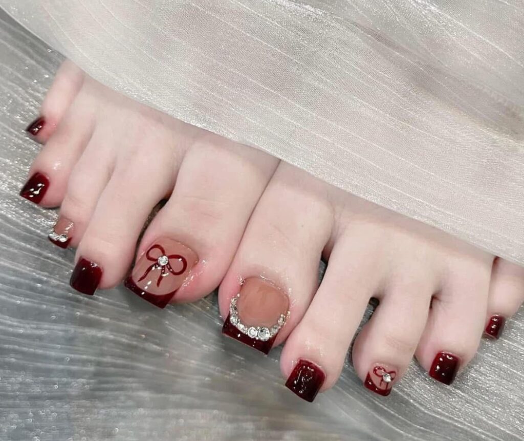 Mẫu nail chân đính đá màu đỏ quyến rũ, kết hợp họa tiết nơ xinh xắn, nổi bật