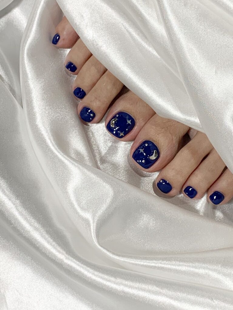 Mẫu nail chân màu xanh navy nhũ lấp lánh ánh sao, huyền bí và cuốn hút.