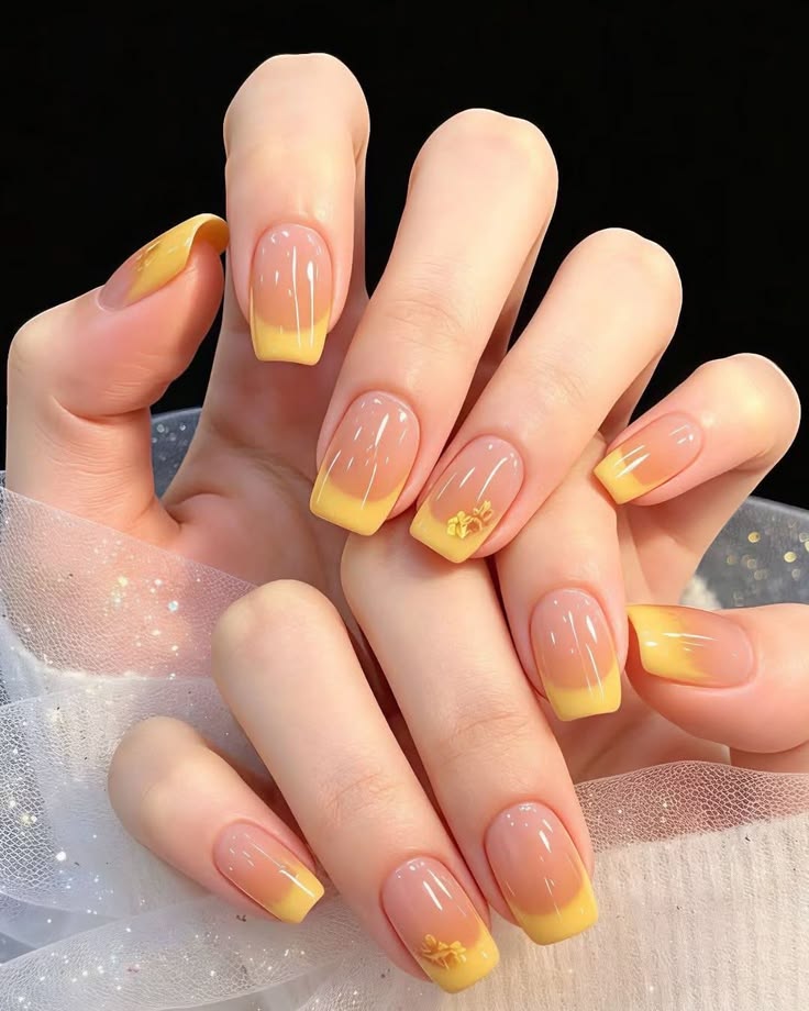 Bộ móng nail đẹp kiểu French tip vàng nắng rực rỡ, điểm xuyết họa tiết hoa nhí ánh nhũ vàng, tươi sáng và tràn đầy năng lượng.