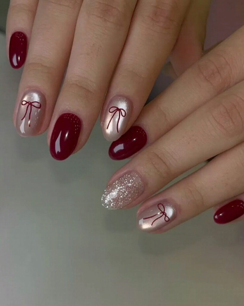 Mẫu nail mắt mèo đỏ đô bóng gương phối cùng móng nude ánh nhũ vẽ họa tiết nơ chỉ mảnh màu đỏ, một móng đính nhũ bạc lấp lánh.