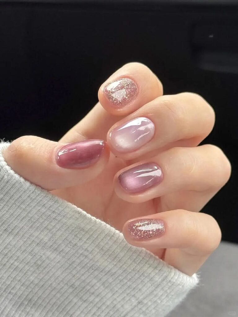Mẫu nail mắt mèo hồng tím ánh kim huyền ảo, hiệu ứng chuyển màu đặc trưng của hiệu ứng mắt mèo, nổi bật trên phông nền đen sang trọng.