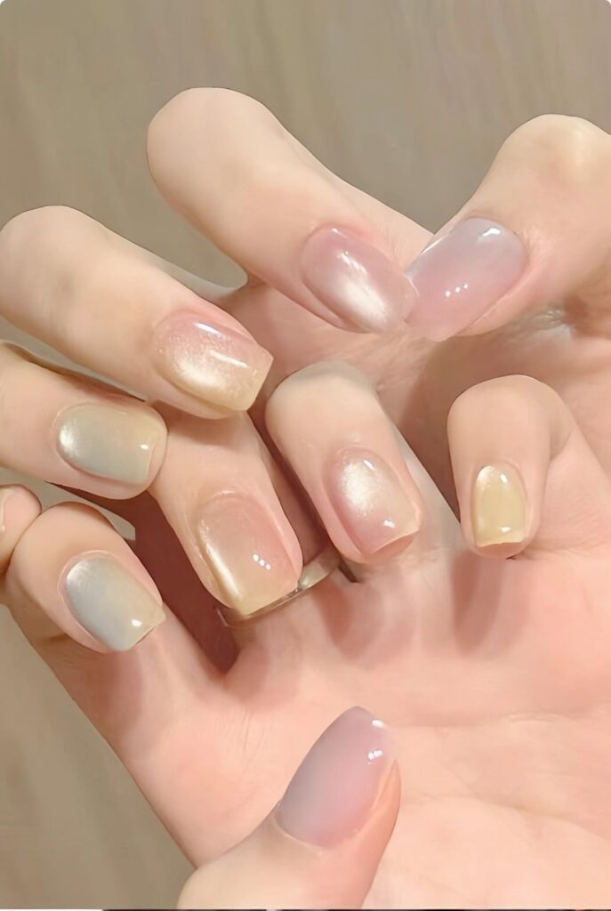 Mẫu nail mắt mèo pastel phối nhiều tông màu nhẹ nhàng như be, vàng nhạt, xám khói và hồng phấn, hiệu ứng ánh kim lấp lánh trên từng móng.