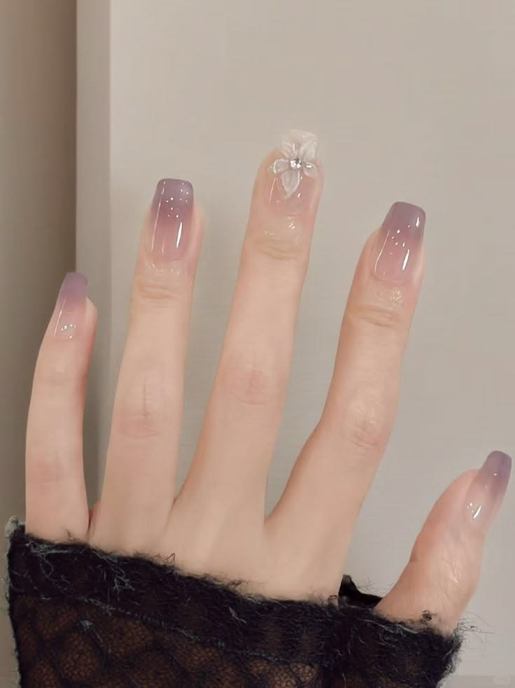 Những mẫu nail đẹp cho móng dài sang chảnh, hot nhất 2026 13 Mẫu nail móng vuông dài ombre tím khói, nhũ trắng lấm tấm và móng nhấn đính hoa trắng 3D, nữ tính lãng mạn và mộng mơ.