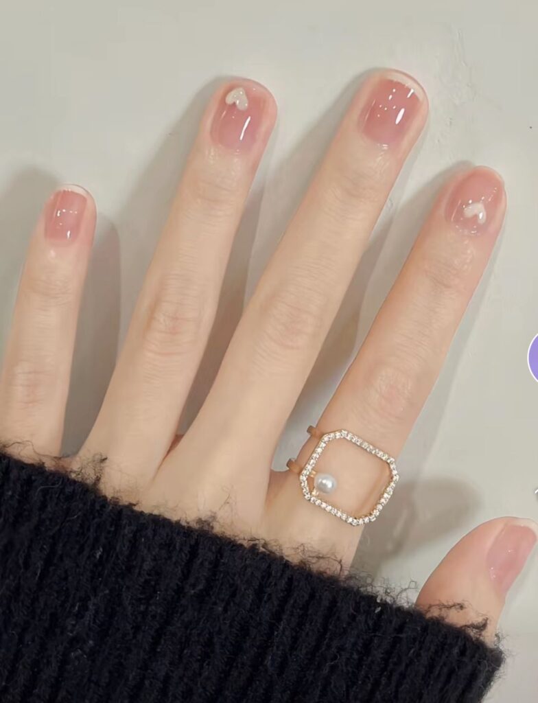 Mẫu nail sơn thạch đơn giản màu hồng đào trong veo, điểm trái tim trắng nhỏ, nhẹ nhàng và tự nhiên.