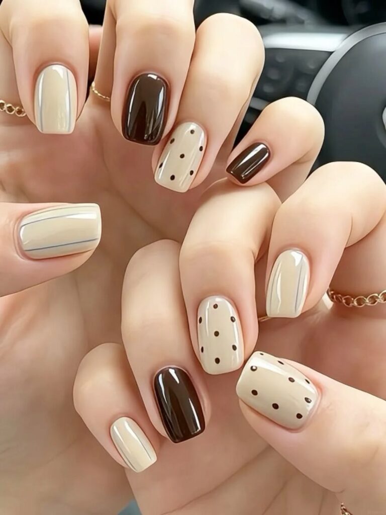 Móng tay nail đẹp phối tông be kem và nâu socola đậm bóng gương, điểm xuyết họa tiết chấm bi cổ điển, ấm áp và tinh tế.
