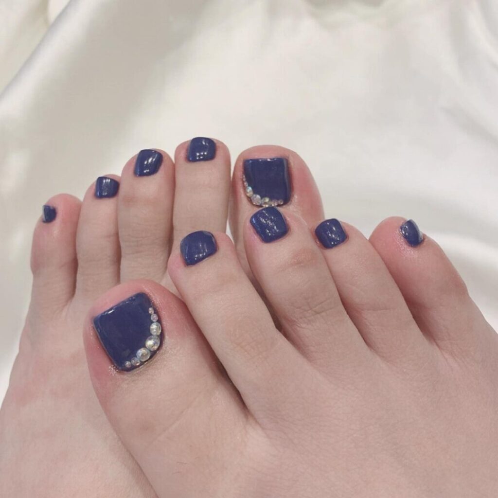 Nail chân màu xanh denim hiệu ứng bóng tráng gương phối đính đá.