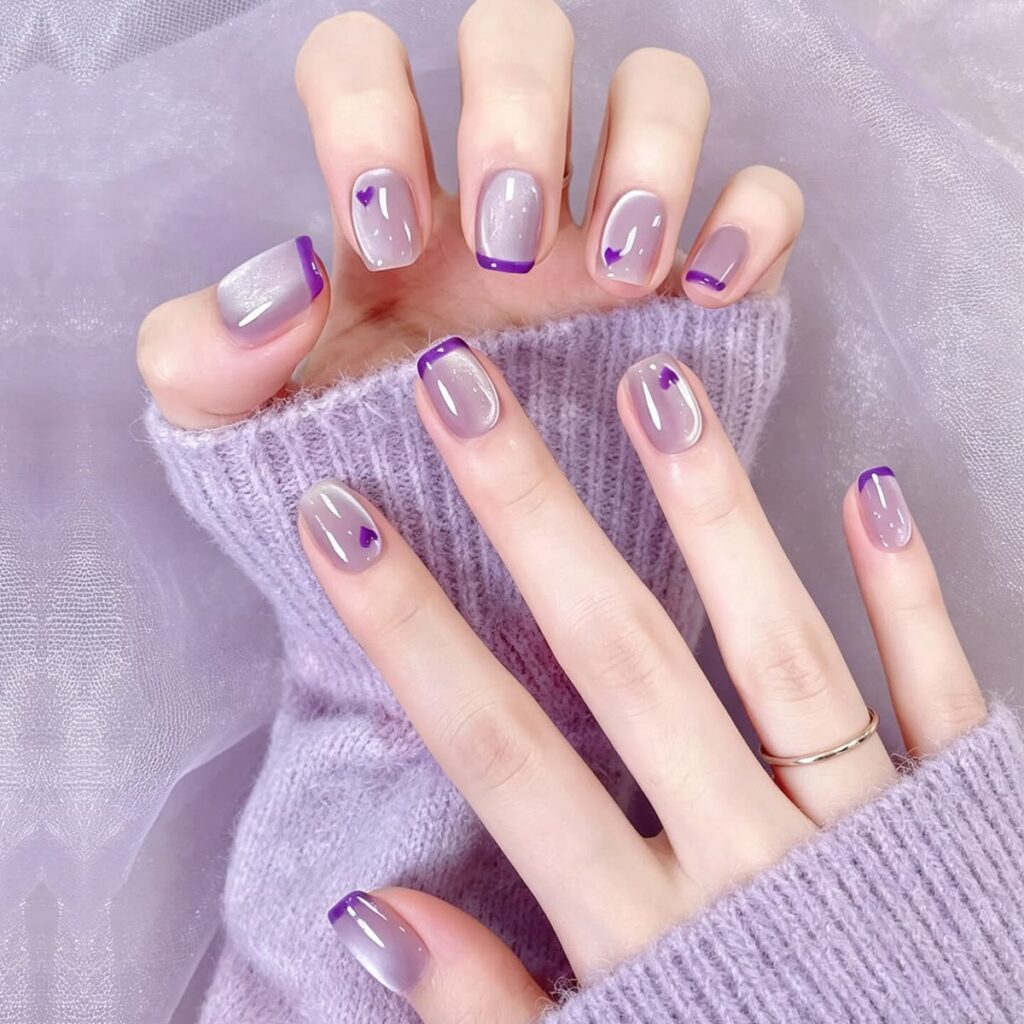 Nail mắt mèo đẹp kiểu French tip viền tím than trên nền xám ánh nhũ, điểm xuyết họa tiết trái tim tím nhỏ xinh, ngọt ngào và tinh tế.