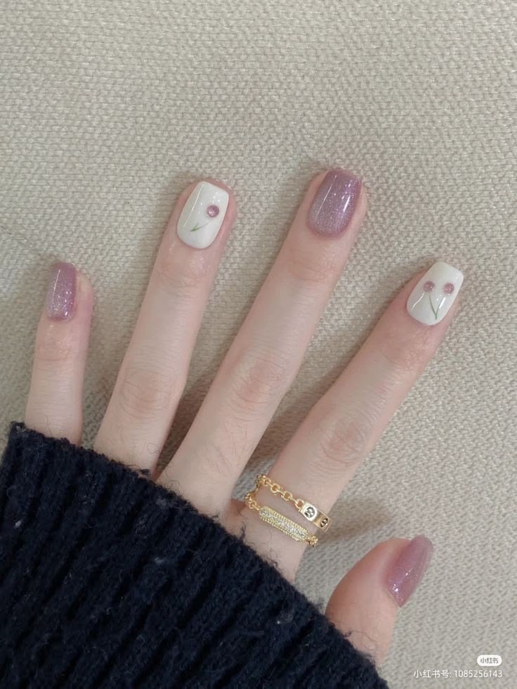 Các kiểu nail đơn giản mà đẹp tông tím mận ánh nhũ lấp lánh phối trắng ngà, điểm xuyết họa tiết hoa dại nhỏ vẽ tay, nhẹ nhàng thanh lịch.