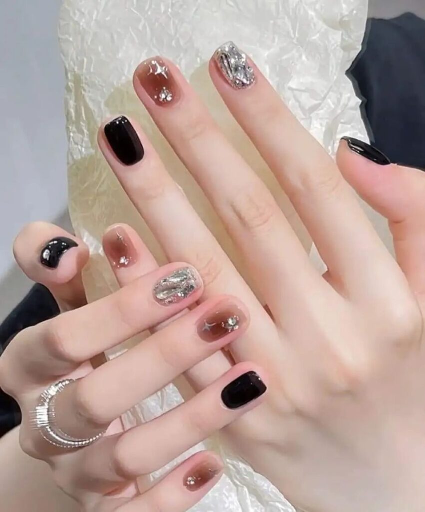 Kiểu nail đẹp phá cách với gam đen bóng gương xen kẽ nail trong suốt ánh khói đính giấy bạc (foil) bạc lấp lánh, sang trọng.