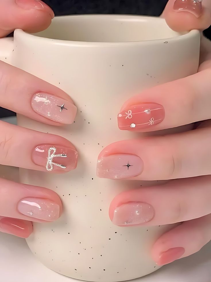 Những mẫu nail đẹp cho móng ngắn tone hồng ánh nhũ, đính nơ bạc và ngôi sao bốn cánh, sang trọng, tinh tế.