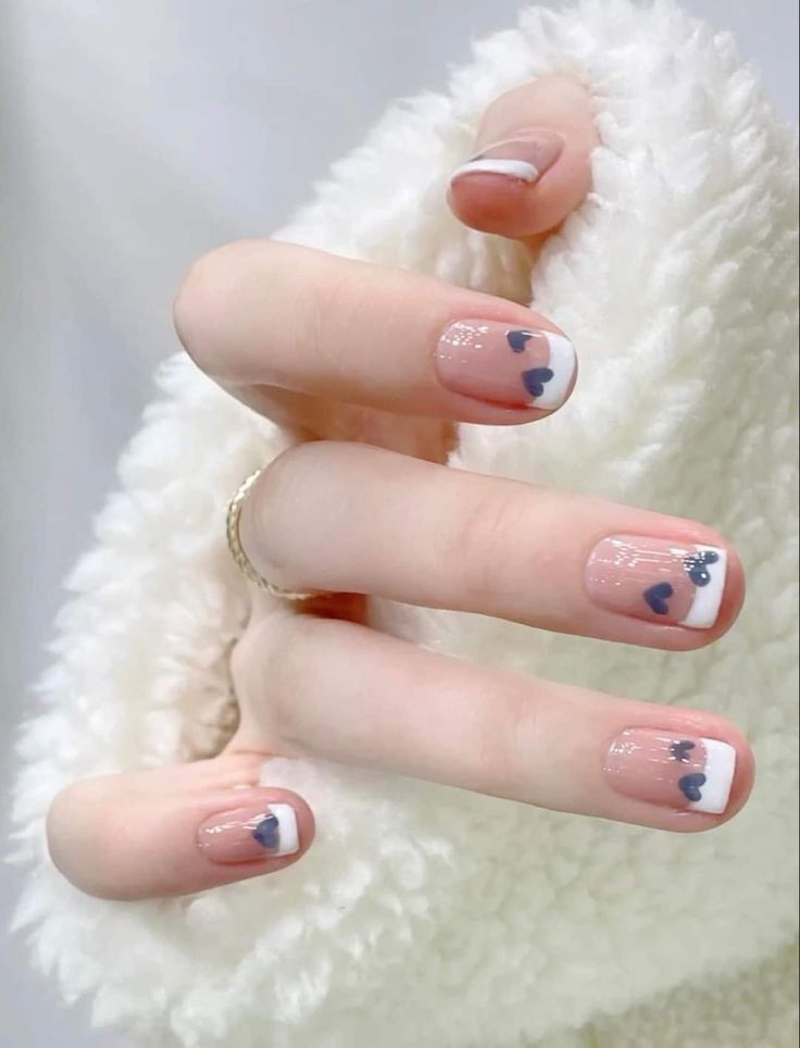 Nail đẹp đơn giản kiểu French tip viền trắng tinh khôi, điểm xuyết họa tiết trái tim xanh navy nhỏ xinh, ngọt ngào và tinh tế.