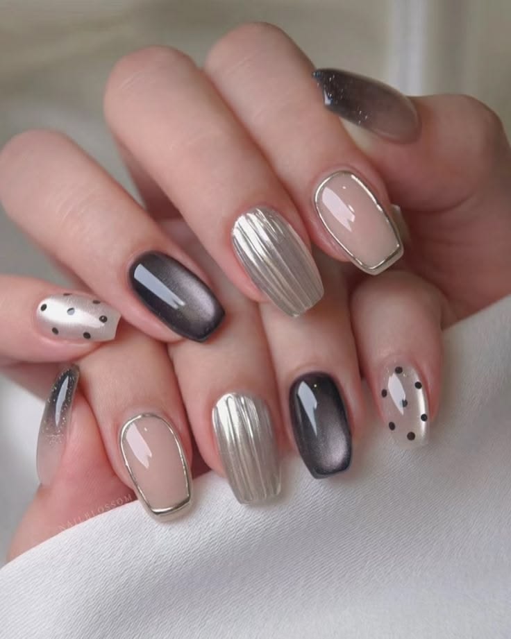 Sơn gel mắt mèo phối ba tông đen, nude viền bạc và bạc chrome ánh kim, điểm xuyết họa tiết chấm bi, tạo vẻ sang trọng hiện đại.